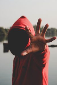 Man in hood without face putting hand out to say stop